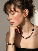 High-quality close-up of Yuè TerraBrio smoky quartz and black tourmaline jewelry under intense direct sunlight, showcasing crystal transparency.