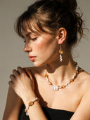 A model showcasing the temple-blessed Solar Abundance jewelry set, including the citrine necklace, matching bracelet, and drop earrings in warm, direct sunlight.