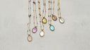 Assorted natural gemstone pendant necklaces arranged on a light textured surface for Yue TerraBrio's Start Here page banner.