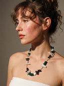 An artistic portrait of a model wearing the temple-blessed Terra Equilibrium necklace in dramatic warm light, highlighting the intimate and protective energy of the stones.